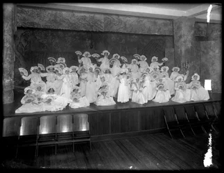 Groep kleine meisjes geposeerd op een klein podium met waaiers, waarschijnlijk het Rooms-Katholieke Weeshuis, Kingsbridge, Bronx, ca. 1911