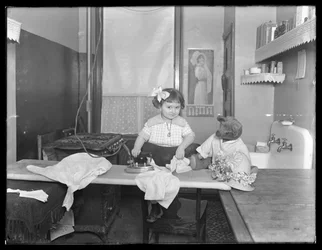 Onbekend klein meisje demonstreert het gebruik van een elektrische strijkijzer, c.1913-14