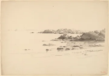 Rotsachtige strand met verre boten